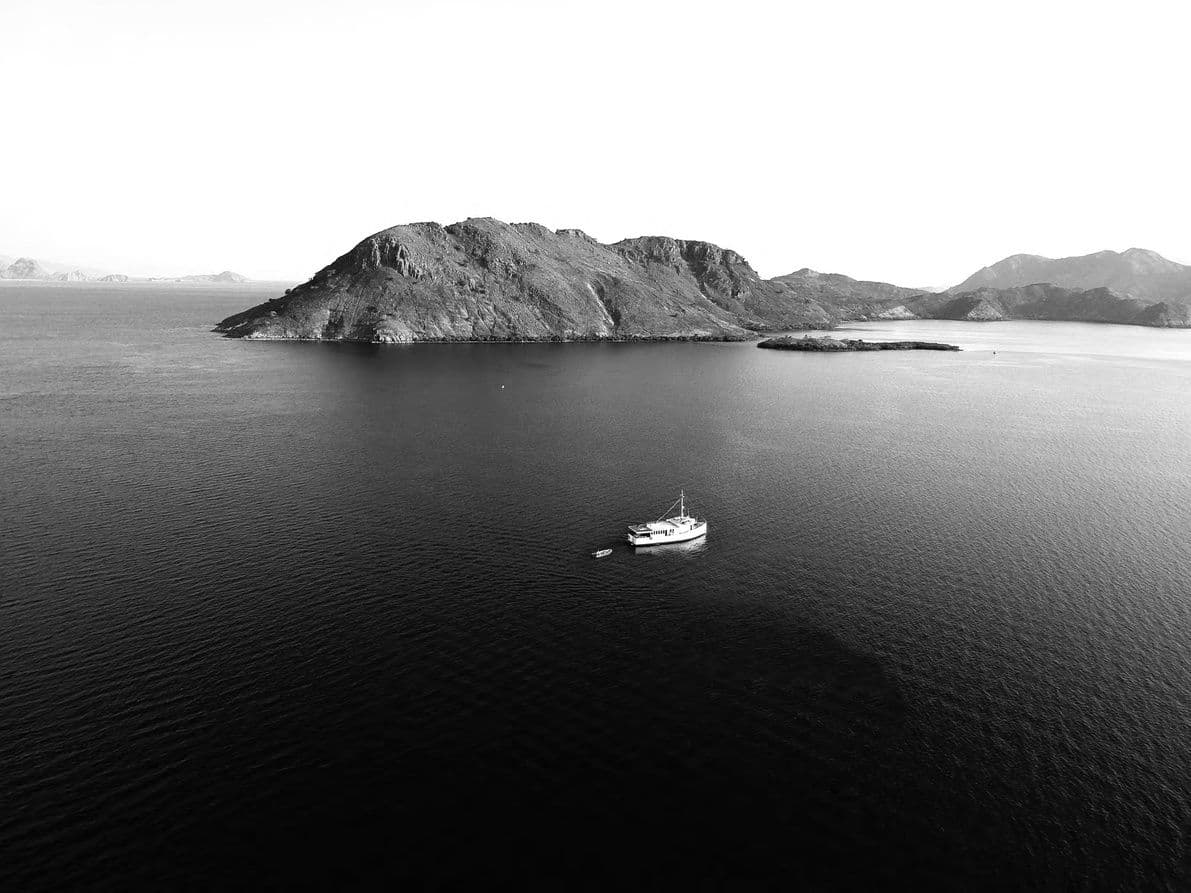 A boat crossing still water below an island